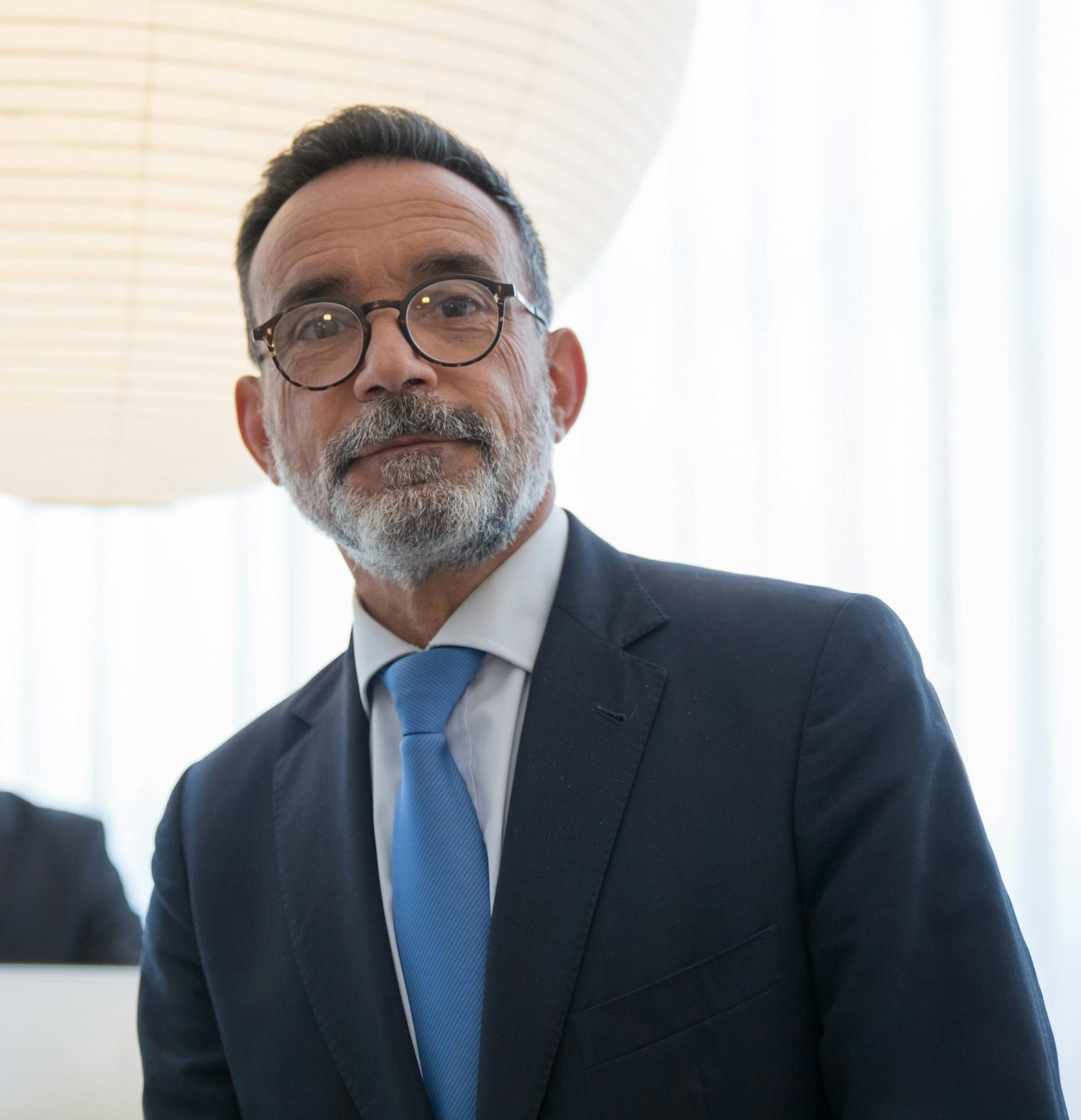Confident senior executive in formal attire with modern office background.